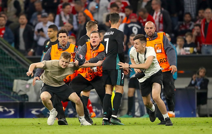 Pitch invaders are chased by stewards past Real Madrid's Cristiano Ronaldo after the final whistle.