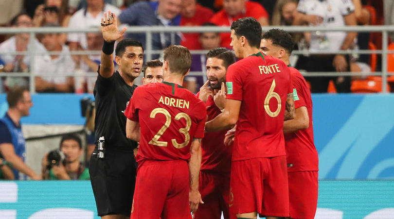 Players of Portugal argue with the referee after a VAR penalty decision.