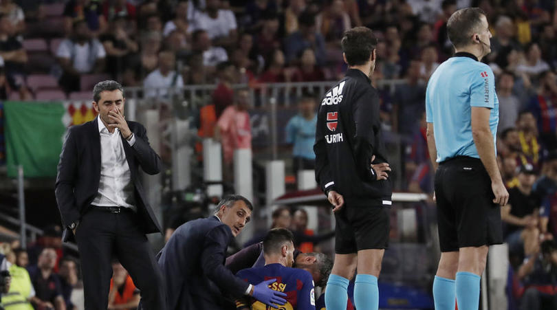 Barcelona's head coach Ernesto Valverde stands near Lionel Messi after he left the field to get treatment on getting hurt during the Spanish La Liga soccer match